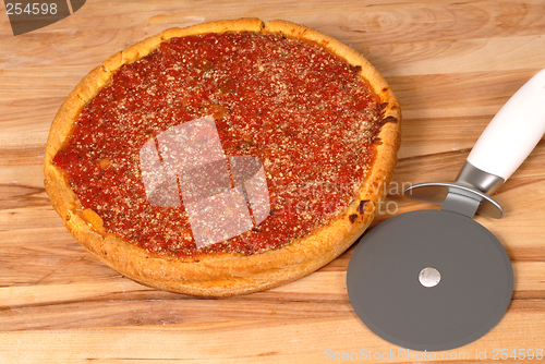 Image of A Chicago style deep dish pizza on a cutting board with cutter