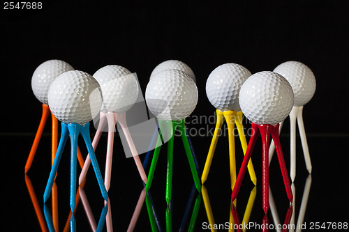 Image of White golf balls and different colored tees