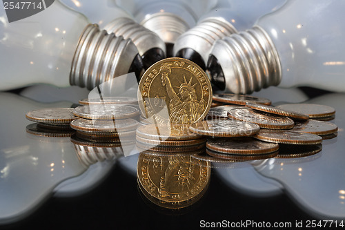 Image of Wasteful bulbs and U.S.  dollar coins 