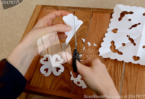 Image of Woman making paper snowflakes at a wooden craft table