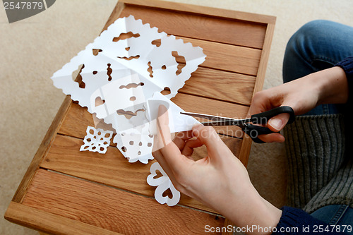 Image of Woman cutting paper into snowflake designs