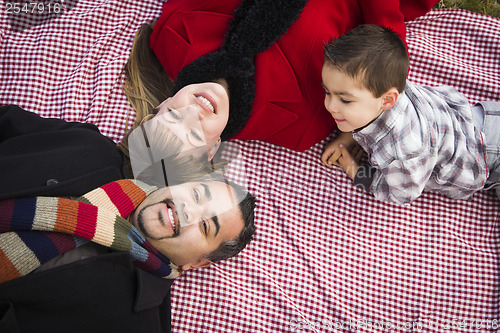 Image of Family in Winter Clothing Laying on Their Backs in Park