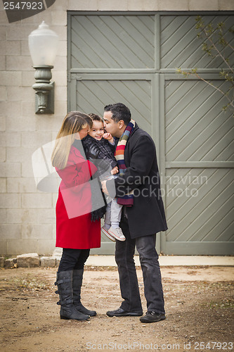 Image of Warmly Dressed Family Loving Son in Front of Rustic Building