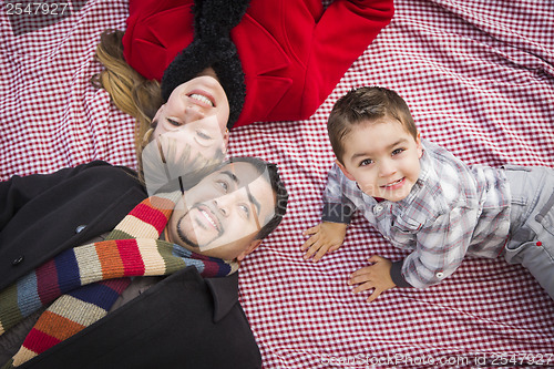 Image of Family in Winter Clothing Laying on Their Backs in Park