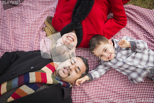 Image of Family in Winter Clothing Laying on Their Backs in Park