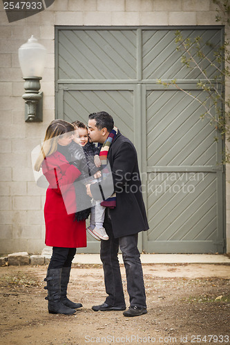 Image of Warmly Dressed Family Loving Son in Front of Rustic Building