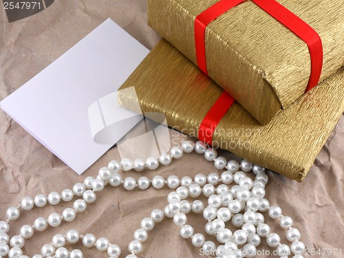 Image of golden gift box with red bow with pearls on old paper