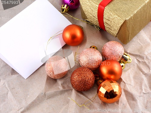 Image of golden gift box with red bow and christmas balls set on old paper