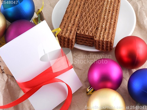 Image of sweet waffles with christmas balls and white invitation card