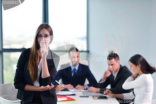 Image of business woman with her staff in background at office