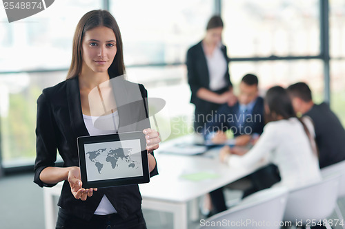 Image of business woman with her staff in background at office