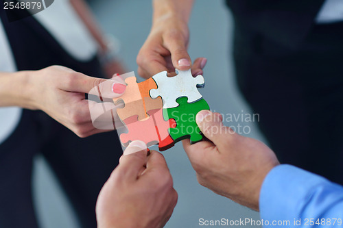 Image of Group of business people assembling jigsaw puzzle