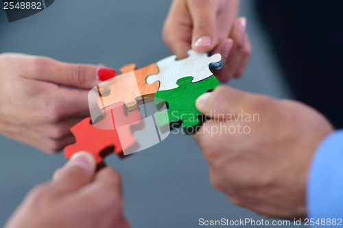 Image of Group of business people assembling jigsaw puzzle