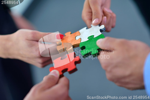 Image of Group of business people assembling jigsaw puzzle