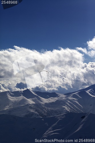 Image of Winter mountain in evening and silhouette of parachutist