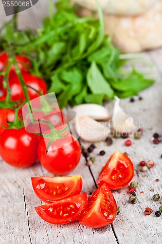 Image of fresh tomatoes, garlic, rucola, peppercorns and buns