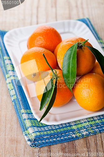 Image of tangerines with leaves in plate