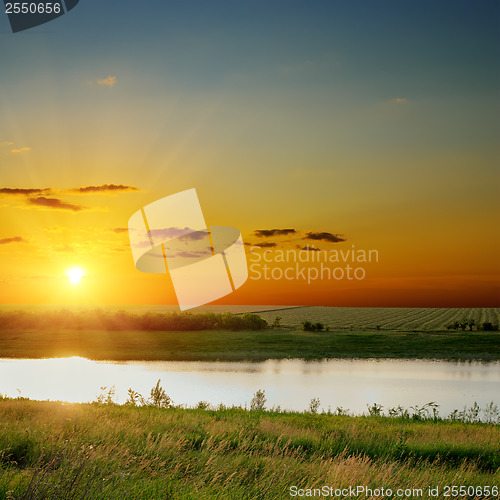 Image of orange sunset over river with green sides