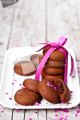 Image of plate of fresh chocolate cookies with pink ribbon and confetti 