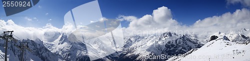 Image of Panoramic view on ski slope and cloudy mountains at sun day