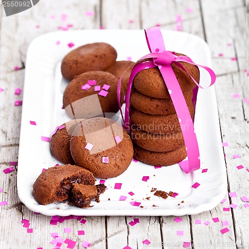 Image of plate of fresh chocolate cookies with pink ribbon and confetti 
