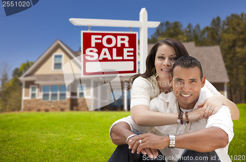 Image of Hispanic Couple, New Home and For Sale Real Estate Sign