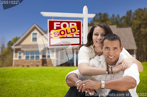 Image of Hispanic Couple, New Home and Sold Real Estate Sign