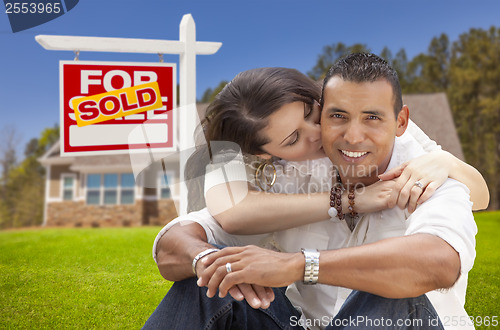 Image of Hispanic Couple, New Home and Sold Real Estate Sign