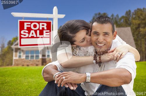 Image of Hispanic Couple, New Home and For Sale Real Estate Sign