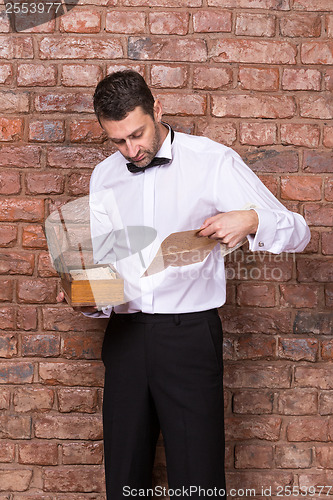 Image of Man reading a document from a wooden box