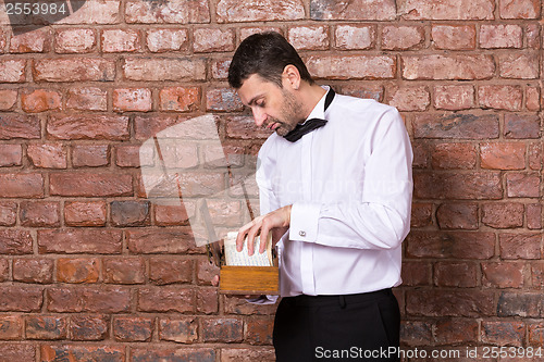Image of Man reading a document from a wooden box