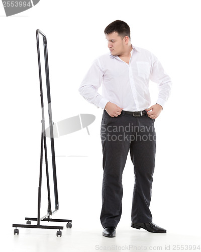 Image of Overweight man admiring himself in a mirror