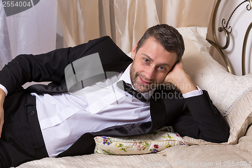 Image of Elegant playboy reclining on a bed