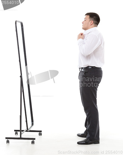 Image of Overweight man admiring himself in a mirror