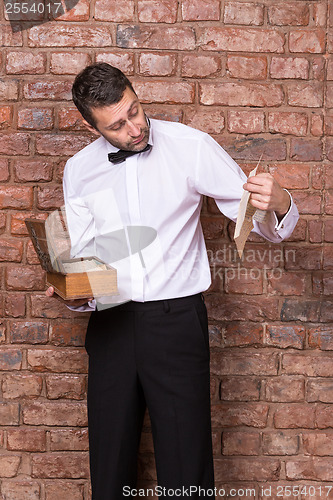 Image of Man reading a document from a wooden box