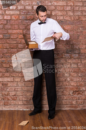 Image of Man reading a document from a wooden box