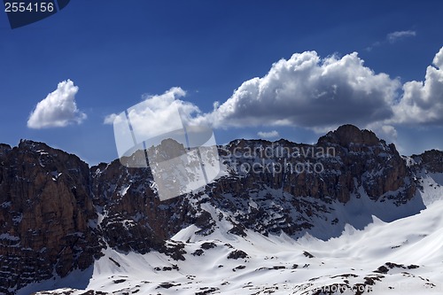 Image of Snowy rocks and blue sky with cloud in sunny spring day