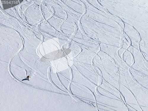 Image of Snowboarder downhill on off piste slope with newly-fallen snow