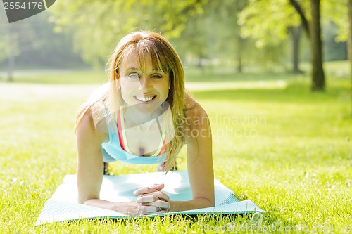 Image of Woman holding plank pose outside