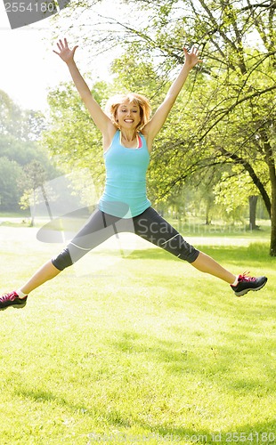 Image of Smiling woman jumping in park