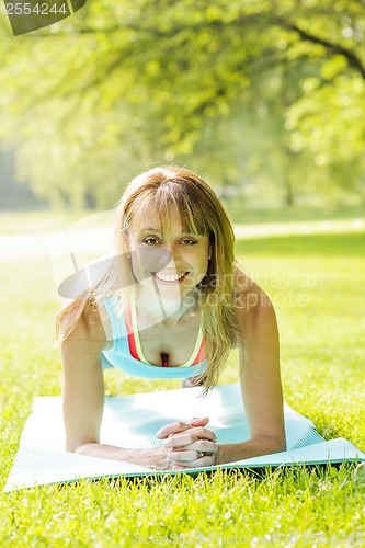 Image of Woman holding plank pose outside