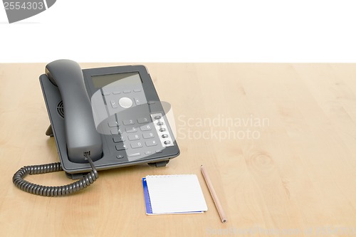 Image of phone on desk with notepad on wooden desk