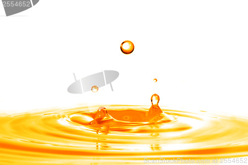 Image of drop falling into orange water with splash isolated on white