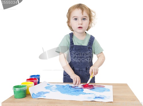 Image of cute girl painting on small desk looking to camera
