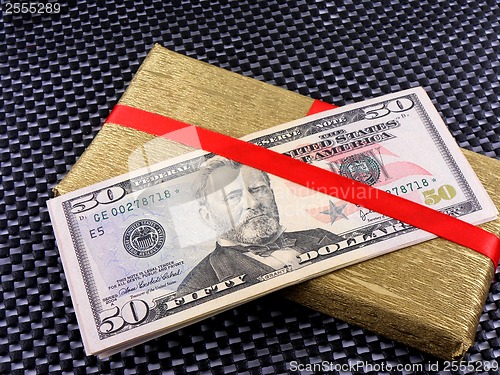 Image of Holiday bonus. Money on red bow decorated gift box