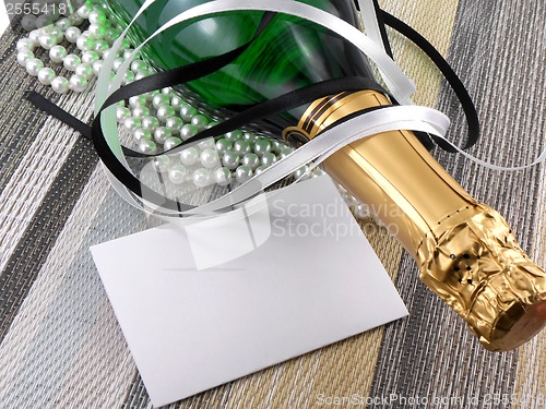 Image of champagne bottle with christmas present, holiday invitation card