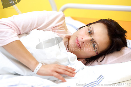 Image of smiling middle-aged woman lying in hospital