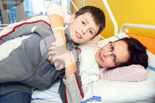 Image of sad middle-aged woman lying in hospital with son