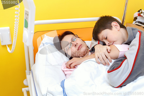 Image of sad middle-aged woman lying in hospital with son