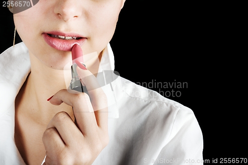 Image of Young woman applying lipstick